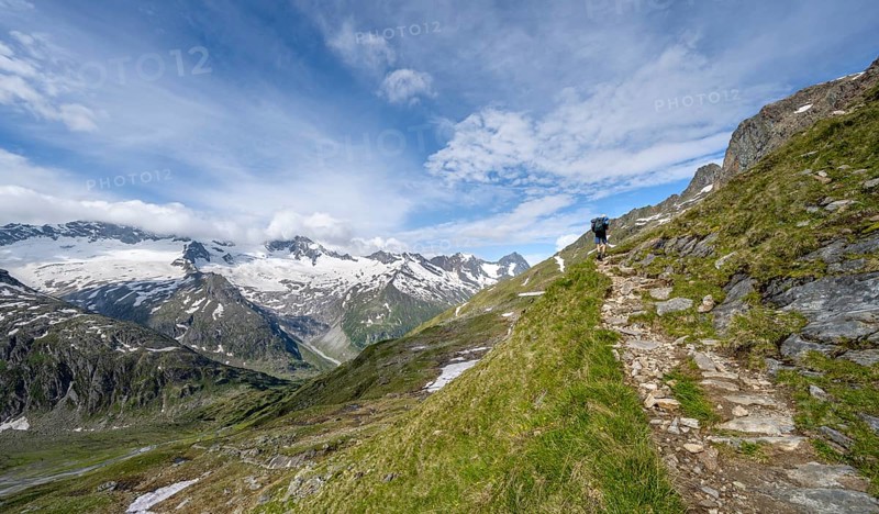 Mountaineer on hiking trail in picturesque mountain landscape, mountain peak with snow and glacier Hornkees and Waxeggkees, summit Hornspitzen and Großer Möseler, Berliner Höhenweg, Zillertal Alps, Tyrol, Austria, Europe