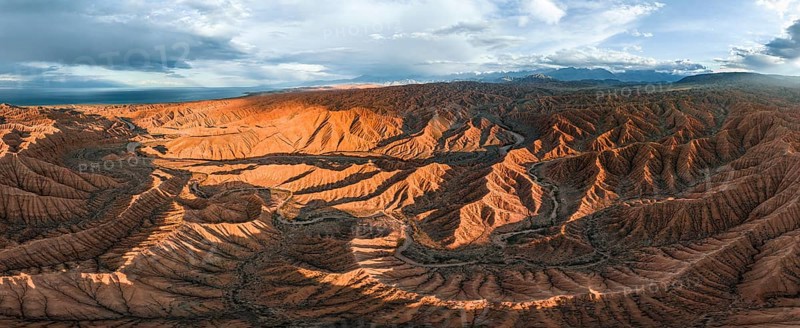 Panorama, landscape of eroded hills at Lake Issyk Kul, badlands at sunset, mountain peaks of the Tian Shan Mountains in the background, aerial view, Canyon of the Forgotten Rivers, Issyk Kul, Kyrgyzstan, Asia