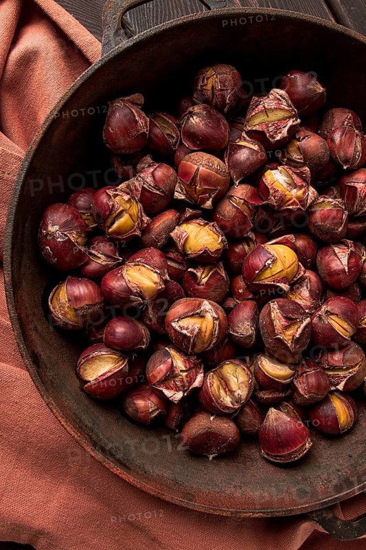 Roasted chestnuts, in an iron pan, wooden table, top view, no people, rustic style