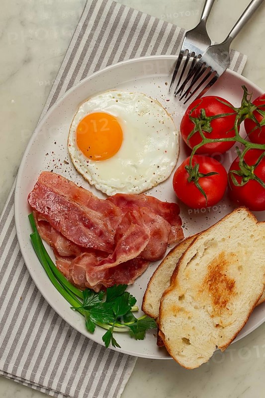 Breakfast, fried egg, bacon and bread, with cherry, on a light background, homemade, no people