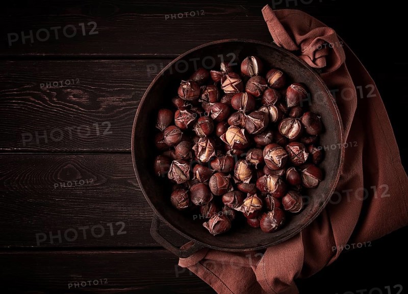 Roasted chestnuts, in an iron pan, wooden table, top view, no people, rustic style