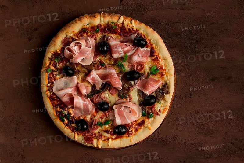 Pizza with prosciutto and mushrooms, bacon, olives, homemade, top view, no people
