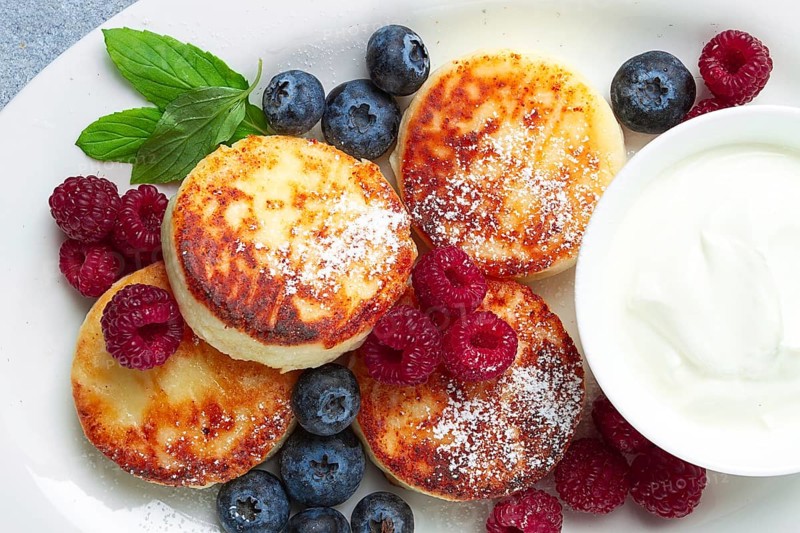 Breakfast, cottage cheese cakes, with fresh berries, and sour cream, top view, close-up, no people