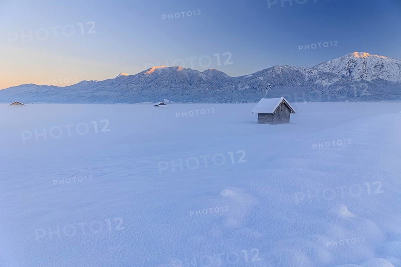 Hut in the snow in front of mountains, evening light, view of Rabenkopf and Jochberg, Schlehdorf, Alpine foothills, Upper Bavaria, Bavaria, Germany, Europe