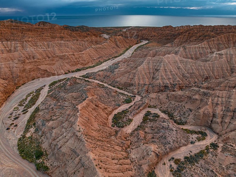 River bed runs through a landscape of eroded hills, badlands, Issyk Kul Lake in the background, aerial view, Canyon of the Forgotten Rivers, Issyk Kul, Kyrgyzstan, Asia