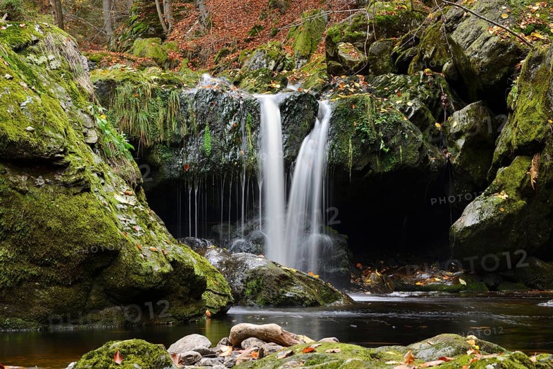 Waterfall falling into a moss-covered grotto, surrounded by autumn leaves, Bavarian Forest National Park