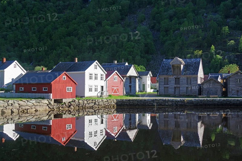 A small village with red and white houses reflected in the calm fjord waters, heritage-protected building, Laerdal, Sognefjord, Norway, Europe