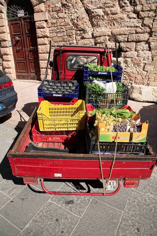 Ape vehicle of a greengrocer, loaded with fruit and vegetables, in the historic centre of Assisi, Umbria, Italy, Europe
