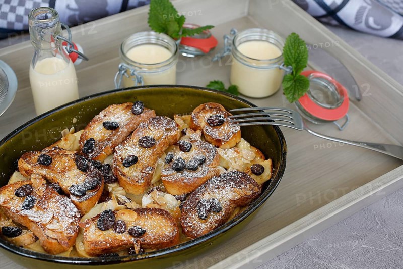 Swabian cuisine, Ofenschlupfer, sweet main course or dessert, dessert, sweet dish, typical Swabian, classic, from the oven, casserole, leftovers, rolls with sultanas, apples, gratinated, vanilla sauce, icing sugar, served on a tray, home cooking, traditional cuisine, food photography, studio, Germany, Europe
