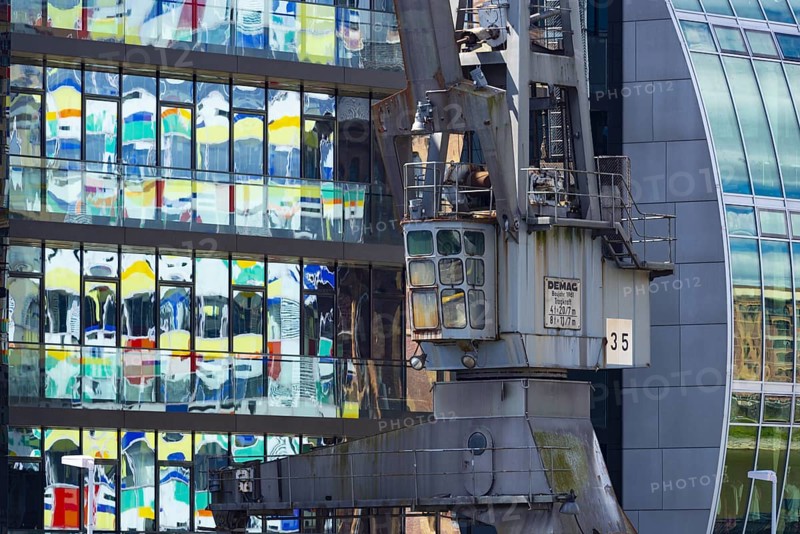 Old crane in front of the glass façade of an office building, reflecting the Colorium high-rise, façade with coloured glass panels, architect William Alsop, Julo-Levin-Ufers in Medienhafen, Düsseldorf, North Rhine-Westphalia, Germany, Europe