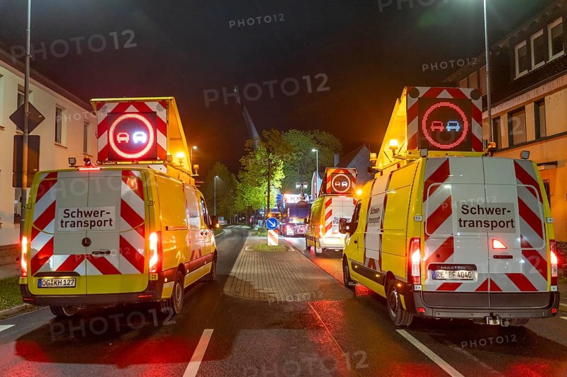 Securing and escort vehicles during the transport of a 68 metre long, 22 tonne blade of a wind turbine, here in Breckerfeld-Waldbauer, with a self-propelled blade-lifter vehicle, over a 40 km route, over 2 nights, in the Bergisches Land, through towns, villages, on country roads, narrow through roads, to the construction site of the wind turbine near Hagen, North Rhine-Westphalia, Germany, Europe