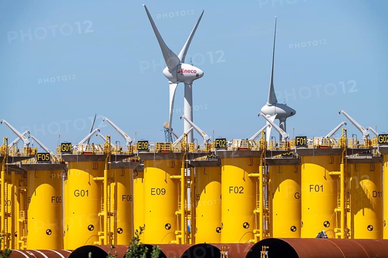 Transhipment centre for offshore wind turbines, which are transported here by the manufacturer and then shipped by special ships to the construction sites of the wind farms in the North Sea, here, yellow, so-called Transition Pieces Jackets, which are mounted on the monopile foundations driven into the seabed, on which the actual wind turbine is then mounted, in the port area of Vlissingen-Oost, Netherlands