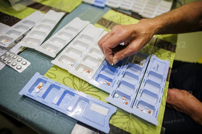 Symbolic photo on the subject of taking medication in old age. Two senior citizens sort various tablets into pill boxes at home to take for the next 16 days. Berlin, 27.07.2024