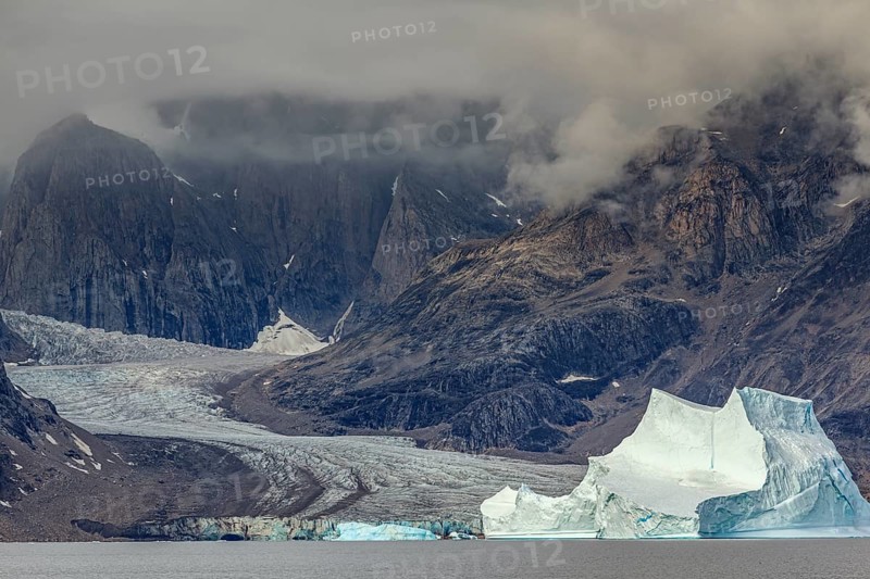 Large icebergs in fjord in front of steep mountains, glacier tongue, cloudy mood, summer, Scoresby Sound, East Greenland, Greenland, North America