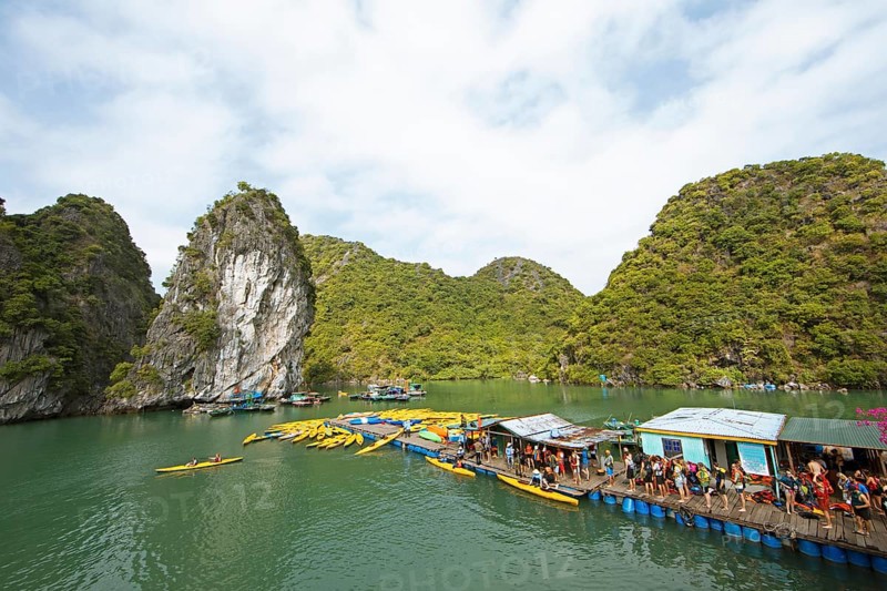 Holidaymakers queue for a kayak on a jetty, behind the karst rocks in Lan Ha Bay, Halong Bay, Vietnam, Asia