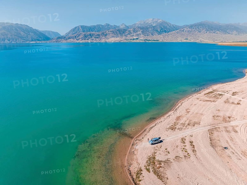 Tourists at the lake with car, aerial view, erosion landscape at the river Naryn, Toktogul reservoir, Kyrgyzstan, Asia