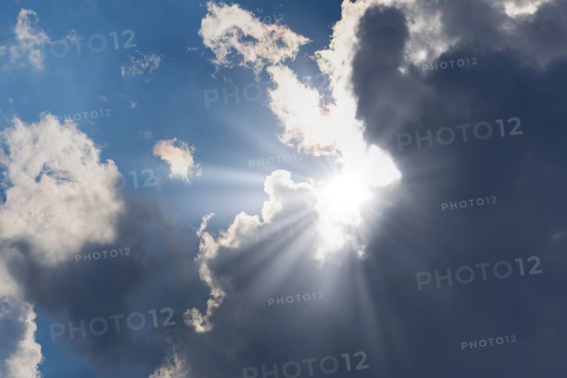 Rain clouds with sun shining through, rays of sunshine, blue sky