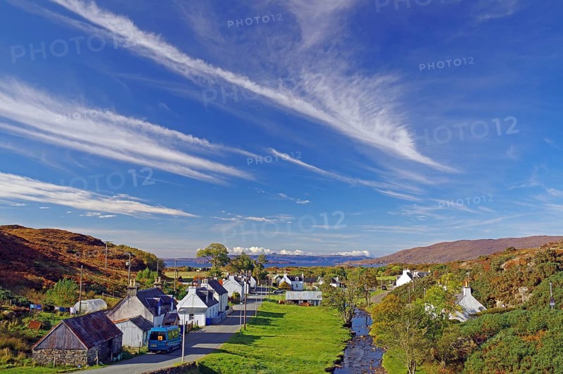 View of a small village on a road with houses, trees and a river under a blue sky with clouds, autumn, October, Highlands, Plockton, Scotland, United Kingdom, Europe