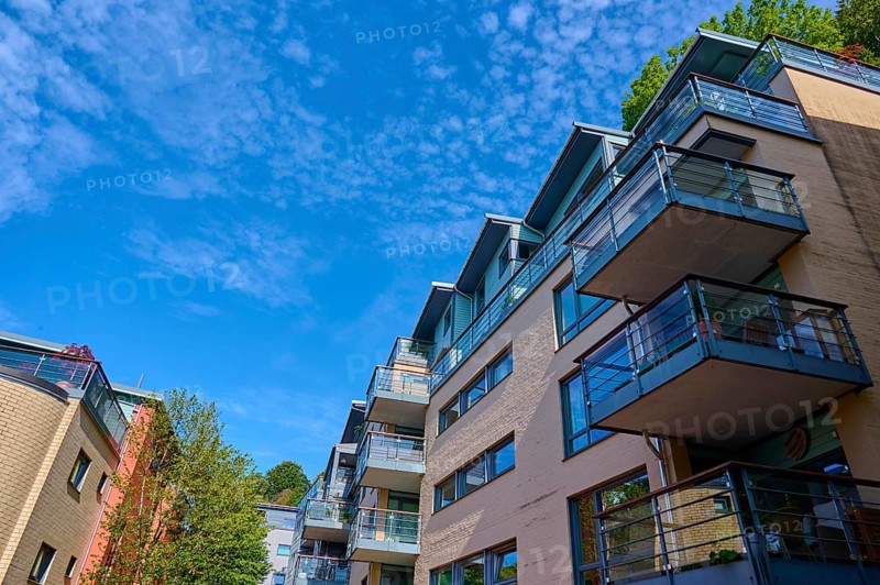 Modern residential building with several balconies and glass railings under a blue sky with clouds in a cityscape, Bergen, Vestland, Norway, Europe