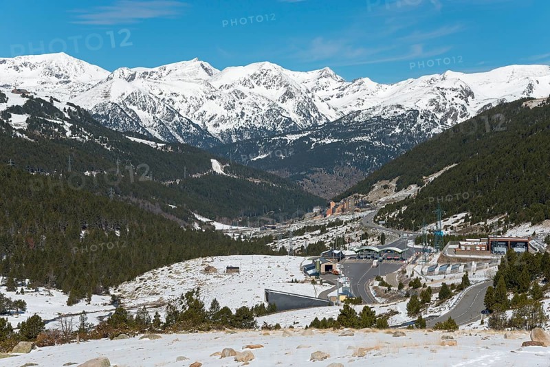 Blick auf eine verschneite Berglandschaft mit Wäldern und Straßen unter einem klaren blauen Himmel, Mautstation für Tunnel, Pyrénées-Orientales, Encamp, Fürstentum Andorra, Pyrenäen