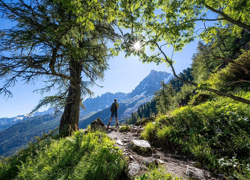 Hiker on hiking trail with sun star, hiking trail La Jonction, behind summit of Aiguille du Midi, Chamonix, Haute-Savoie, France, Europe