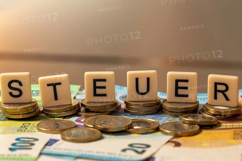 Symbolic image of taxes: The word tax is written on euro coins with letter cubes