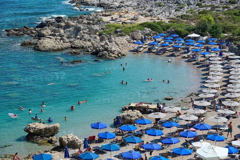 Well frequented beach with many blue parasols and swimmers in the emerald green sea under the midday sun, Anthony Quinn Bay, Vagies Bay, Rhodes, Dodecanese, Greek Islands, Greece, Europe