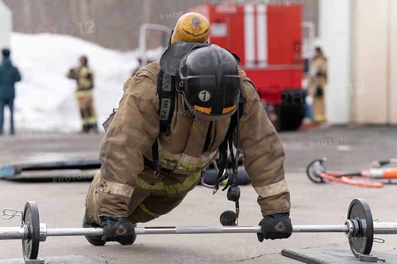 PETROPAVLOVSK CITY, KAMCHATKA PENINSULA, RUSSIA, APR 19, 2019: Strong russian firefighter-rescuer Emercom of Russia press from barbell. Firefighters and rescuers (fire-fighting) sport competitions