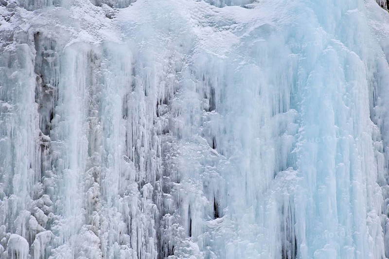 Texture of blue icicles on icy wall of rocks