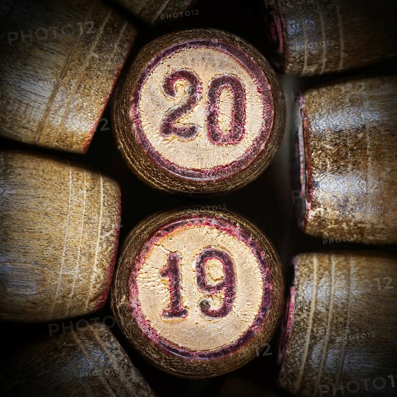 Wooden vintage lotto kegs with two numbers 20 and 19 as symbol of 2019 year. Close-up top view of 2019 New Year inscription in circle with pink trim. Vignette and trendy brown toning