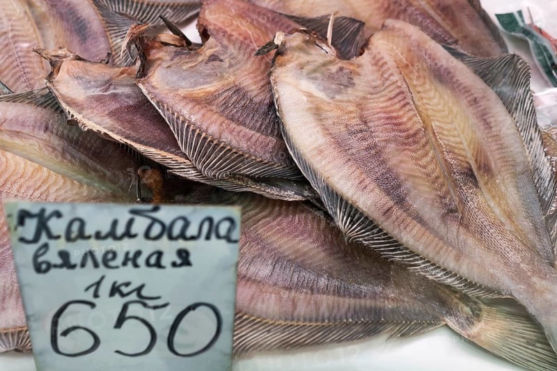 PETROPAVLOVSK CITY, KAMCHATKA PENINSULA, RUSSIAN FAR EAST, 20 MAY, 2018: Close-up view of dried salted flatfish with price on counter at fish market. Concept: delicious, fish market, Asian cuisine