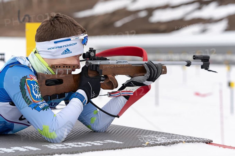Sportsman biathlete Morilov Mikhail Khanty-Mansiysk aiming rifle shooting prone position. Biathlete in shooting range. Regional youth biathlon competitions East Cup. Kamchatka, Russia, April 12, 2019, Europe
