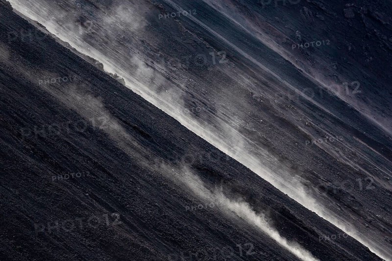 Smoke rises diagonally from the slope of a volcano