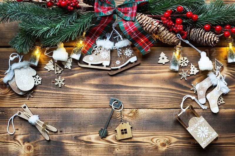 House key with keychain cottage on a festive eco friendly, natural background with Christmas tree. Happy New Year-red background, gift, greeting card. Purchase, construction, relocation, mortgage
