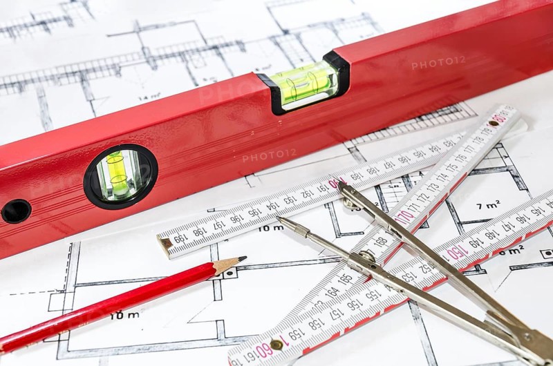 Spirit level, pencil, yardstick and compass calipers on a construction plan