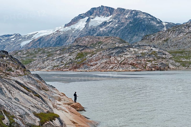 Inuit hunters fishing at the fjord in front of a mountainous landscape, at the Inuit settlement Tiniteqilaaq or Greenlandic Tiilerilaaq, Sermilik Fjord, East Greenland, Greenland, North America