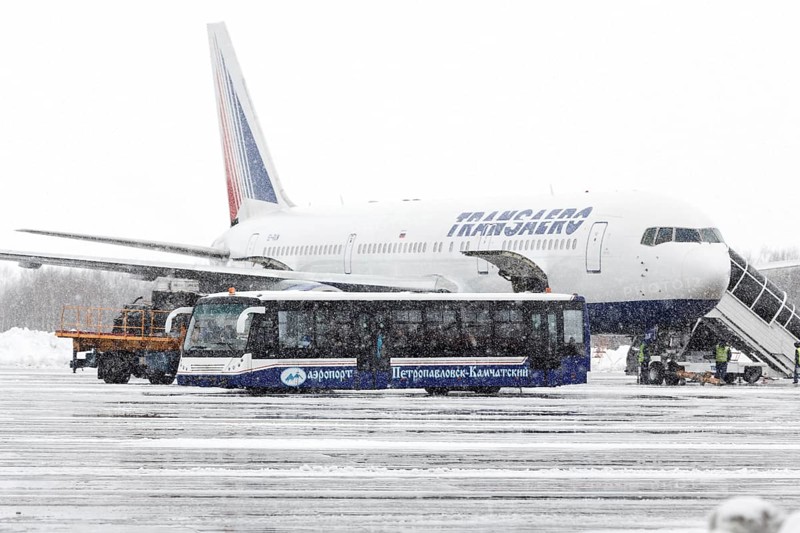 PETROPAVLOVSK, KAMCHATKA, RUSSIA, MARCH 19, 2015: Airfield bus labeled Airport Petropavlovsk-Kamchatsky transports passengers flew airplane Boeing 767 Transaero Airlines during a snowfall and poor visibility