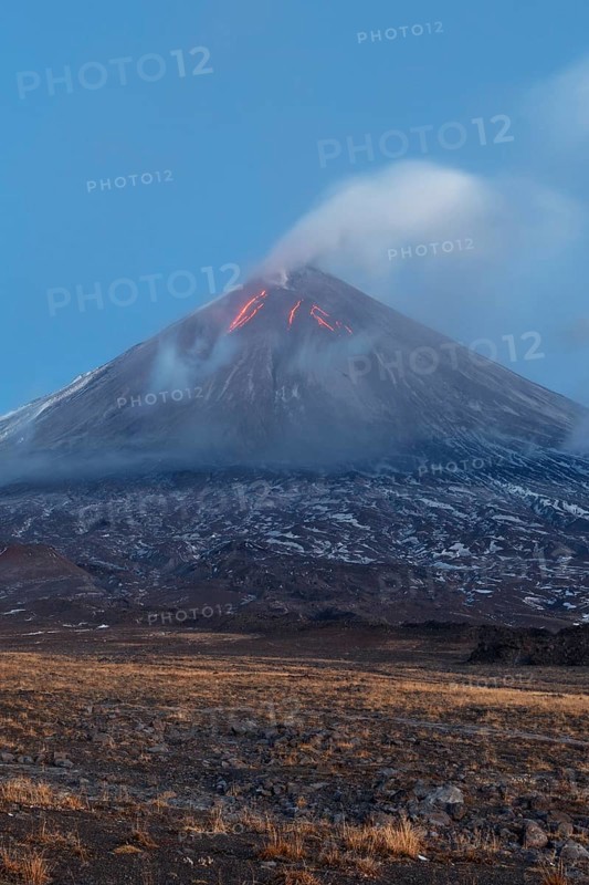 Volcanic landscape of Kamchatka: eruption Klyuchevskoy Volcano, lava flows on slope of volcano, plume of gas, steam, ash from crater. Kamchatka Peninsula, Russia, Klyuchevskaya Group of Volcanoes, Europe