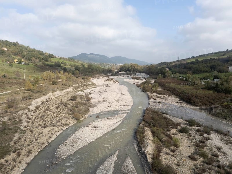 Muddy water flowing in the arda river near mignano val tolla in piacenza, italy, creating small waves and rapids on a sunny day