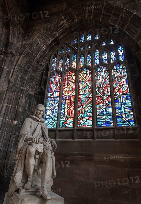 Manchester, England, September 23, 2016: Statue of Humphrey Chetham and colorful stained glass window inside the famous Manchester Cathedral