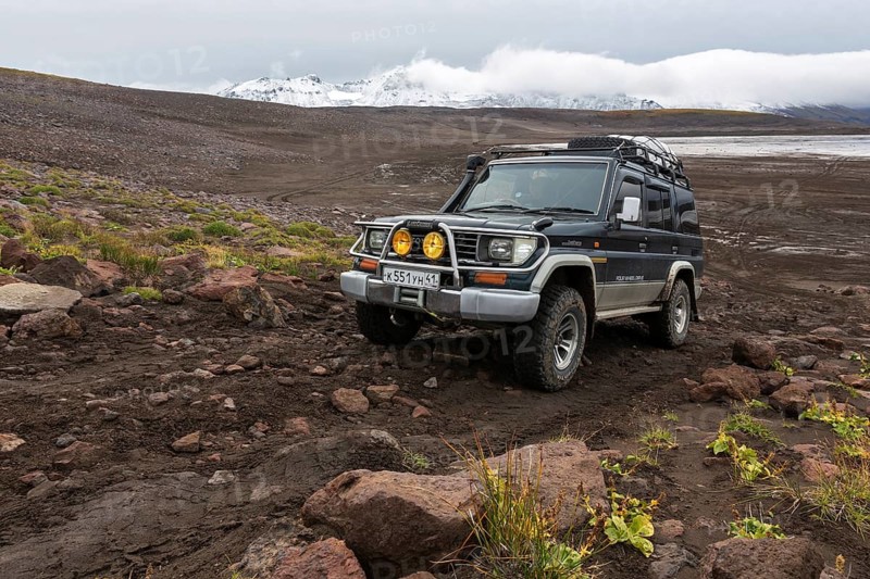 KAMCHATKA PENINSULA, RUSSIA, SEP 17, 2016: Extreme off-road expedition auto Toyota Land Cruiser Prado (70 series) driving on mountain road on background of volcanic landscape in cloudy autumn weather