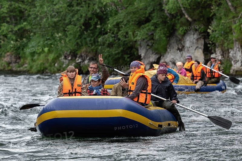 FAST RIVER, KAMCHATKA PENINSULA, RUSSIAN FAR EAST, JULY 15, 2016: Summer rafting on Kamchatka in gloomy cloudy weather: rafting boat with tourists on board floats on waves on mountain river