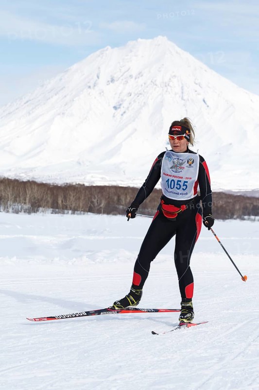 PETROPAVLOVSK CITY, KAMCHATKA PENINSULA, RUSSIA, FEB 10, 2018: Sportswoman skier running along the winter ski track on background of Koryak Volcano. All-Russia mass ski race, Ski Track of Russia
