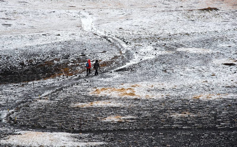 Unrecognized people trekking on a curved nature trail covered in snow in Iceland