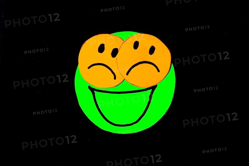 Paper cutouts of circles with faces drawn on black background. concept of pretending to be happy but having problems and being sad. Mental health