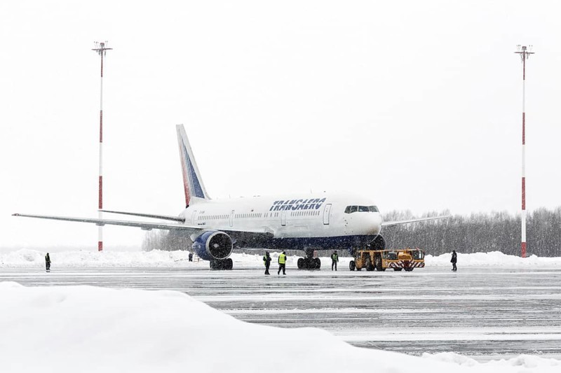 PETROPAVLOVSK-KAMCHATSKY, KAMCHATKA, RUSSIA, MARCH 19, 2015: Airdrome trucks pulling airplane Boeing-767 Transaero Airlines at airport of Petropavlovsk-Kamchatsky (Elizovo airport) during a snowfall and poor visibility