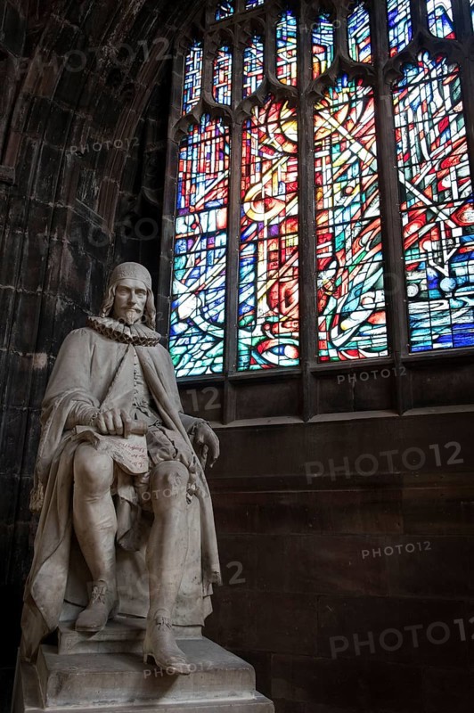 Manchester, England, September 23, 2016: Statue of Humphrey Chetham and colorful stained glass window inside the famous Manchester Cathedral