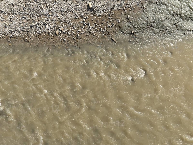 Muddy water is flowing in the arda river near mignano val tolla, piacenza, italy, creating a textured pattern on the surface