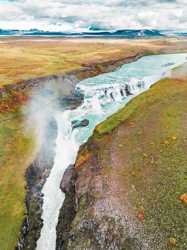 Huge beautiful waterfall Gullfoss, famous landmark in Iceland. River foaming whilst falling down the waterfall, tourist waling by, looking at the waterfall from a view point.