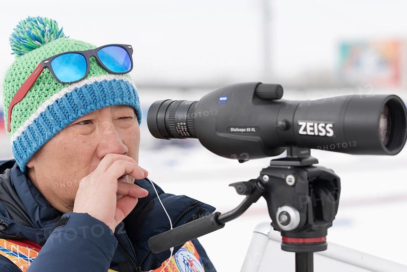 Coach of South Korea biathlon team watches biathletes in monocle at shooting range of biathlon stadium. Junior biathlon competitions East of Cup. Petropavlovsk City Kamchatka, Russia, April 12, 2019, Europe